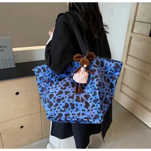 Dettaglio borsa shopper blu con stampa mucca, tracolla e ciondolo di peluche