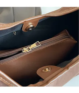 Detail of soft brown leather handbag interior with golden metal zipper and magnetic buckle