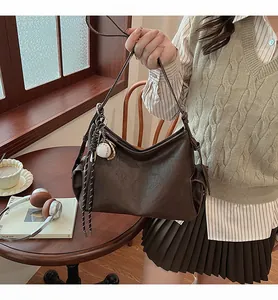 Dettaglio della borsa hobo in pelle testa di moro con charm baseball e corda intrecciata