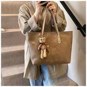 Brown geometric texture tote bag with bear charm shown by model on stairs