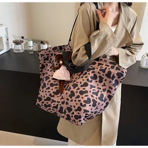 Dettaglio della borsa tote leopardata con ciondolo a peluche in un ambiente caffè