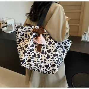 Dettaglio di una borsa tote in tela con stampa mucca e ciondolo a forma di topo