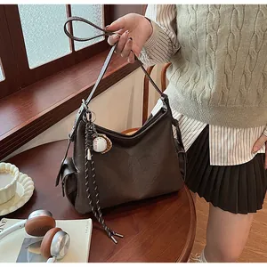 Dettaglio borsa hobo in pelle testa di moro con tracolla intrecciata e ciondolo da baseball