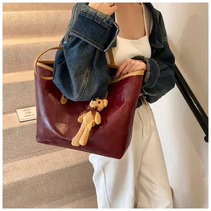 Detail of burgundy patchwork leather tote bag with a cute teddy bear charm pendant