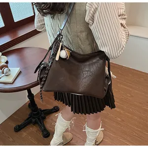 Dettaglio della borsa tote in pelle marrone scuro con ciondolo a tema baseball
