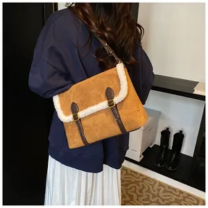 Detail van bruine suède crossbody tas met witte lamswol trim en gesp detail
