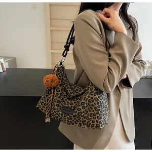 Detail of leopard print tote bag with teddy charm and black leather patch on beige blazer