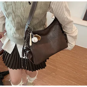 Dettaglio della borsa hobo retrò marrone scuro con ciondolo a tema baseball creativo