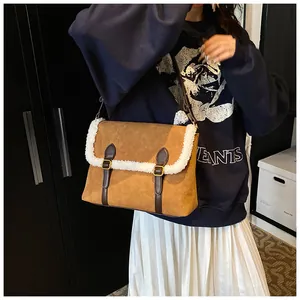 Detail van bruine suède crossbodytas met zachte fleece rand en gouden gesp-accenten