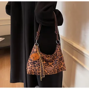 Detail of leopard print tote bag featuring a knotted brown strap and cute dog plush charm