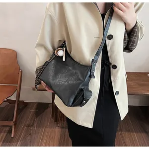 Dettaglio borsa a secchiello vintage nera con cuciture a contrasto e ciondolo baseball