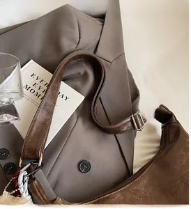 Detail view of brown vintage leather hobo bag with wide shoulder strap and woven charm