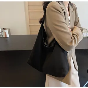 Close-up of a black matte hobo tote bag worn by a model in a professional office outfit