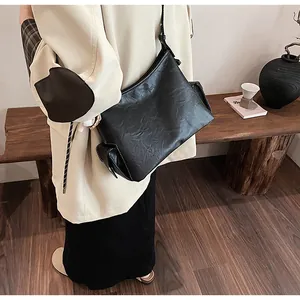 Vista laterale di borsa a secchiello in pelle nera plissettata con tasche laterali