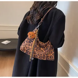 Detail of leopard print tote bag with teddy bear charm and striped tassel rope decoration