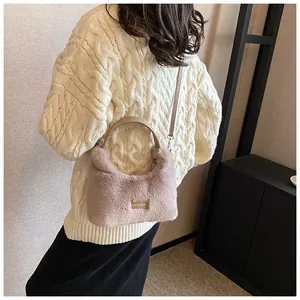 Detail of pink faux fur crossbody bag with leather handle and golden brand metal plate