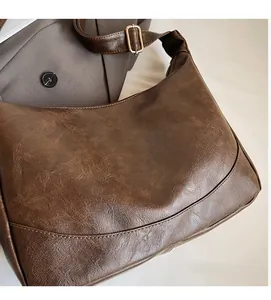 Detail of dark brown retro hobo bag showing faux leather texture and wide shoulder strap