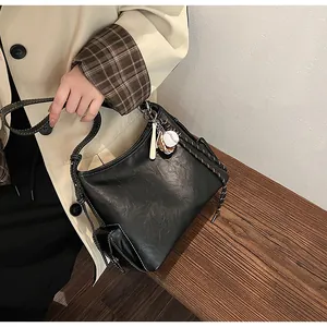 Dettaglio della borsa hobo nera con cuciture a contrasto e ciondolo baseball
