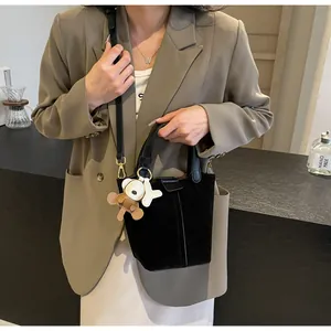 Detail of black matte bucket bag with long leather strap and cute bear charm decor
