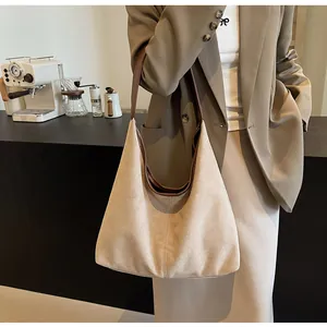 Detail view of large beige frosted leather tote bag with brown straps on a model