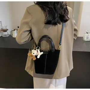 Detail of black suede bucket bag with leather handles and cute bear charm pendant