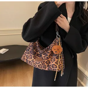 Detail of leopard print hobo bag with teddy bear pendant and tassel on black suit