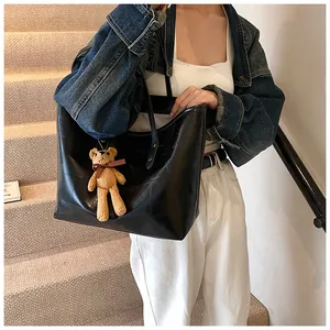 Detail of black large capacity tote bag with texture panels and brown bear charm