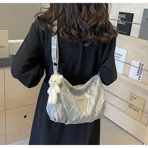 Silberne Metallic-Tragetasche mit Faltenstruktur und weißem Plüschbär-Anhänger