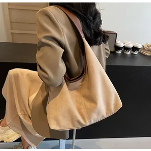 Detail of a large beige suede tote bag with brown straps styled for office commuting