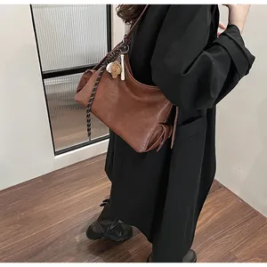 Dettaglio della borsa a secchiello in pelle vintage marrone con corda e ciondolo a orsetto