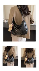 Detail of black faux leather hobo bag with teddy bear charm and adjustable strap