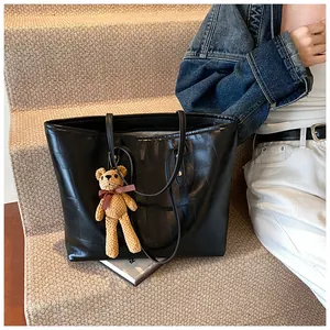 Detail of black geometric patterned tote bag with a cute brown teddy bear keychain