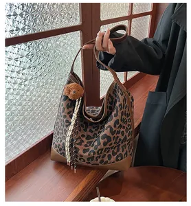 Detail of hobo leopard tote bag with textured canvas, brown leather trim, and bear charm