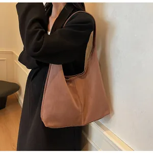 Brown suede shoulder bag shown with a black coat for an elegant winter commute look