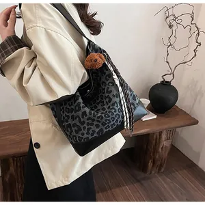 Detail of leopard print tote bag with plush bear charm and leather strap on shoulder