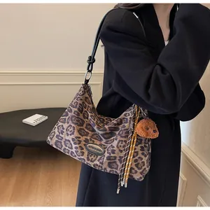 Detail of leopard print hobo bag featuring a leather logo patch and cute bear pendant