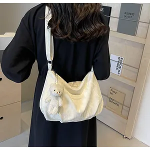 Detail der weißen Hobo-Tasche mit Faltenoptik und Plüschbär-Anhänger am Riemen