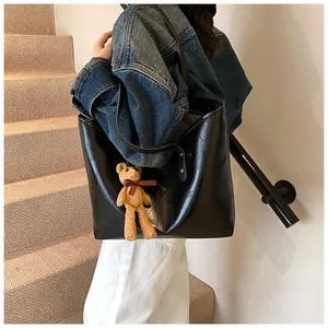 Detail of large black tote bag with geometric stitching and cute brown bear charm