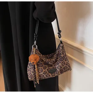Detail of leopard print tote bag featuring a cute plush dog charm and black knot shoulder strap
