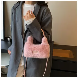 Close-up of pink faux fur crossbody bag featuring a golden engraved metal logo plate