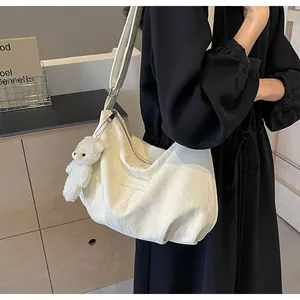 Detail der weißen Samt-Hobo-Tasche mit Plüschbären-Anhänger und verstellbarem Schultergurt