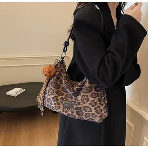 Detail of leopard print tote bag featuring a cute teddy bear charm and woven tassels