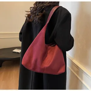 Detail of red suede hobo shoulder bag showing large capacity on model's shoulder