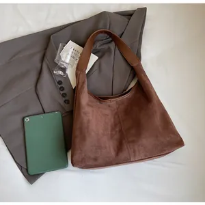 Detail of a deep coffee hobo bag with matte texture and wide strap on a minimal setting