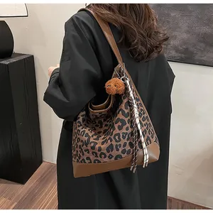 Detail of leopard print tote bag with brown leather trim and cute plush dog pendant