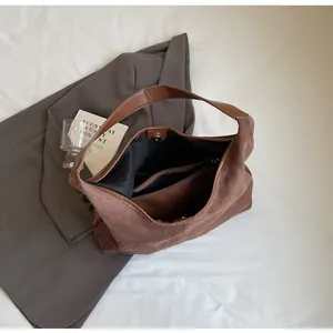 Detail of brown suede tote bag featuring magnetic closure and spacious inner pocket