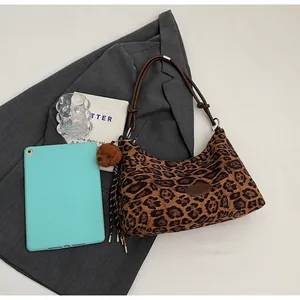 Detail of leopard print tote bag featuring brown shoulder strap and cute plush bear charm