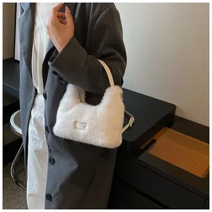Close-up of white plush hobo bag with soft faux fur texture and silver metal brand plaque
