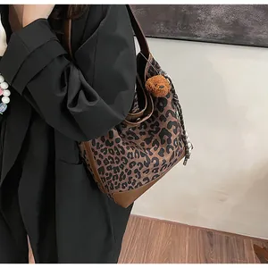 Close-up of leopard print canvas tote with leather trim and brown plush bear charm