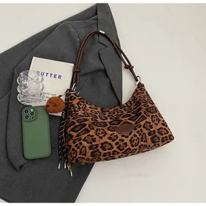 Detail of leopard print hobo bag with braided straps and brown teddy bear charm accessory